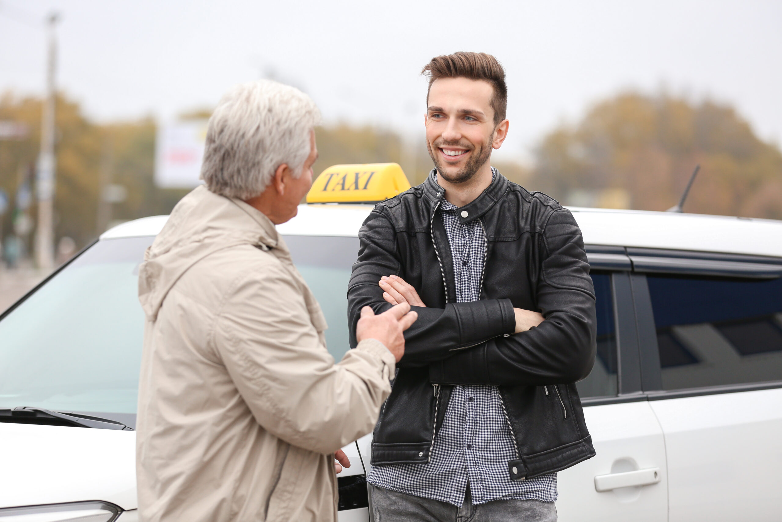 Taxi drivers standing in front of a taxi in conversation.